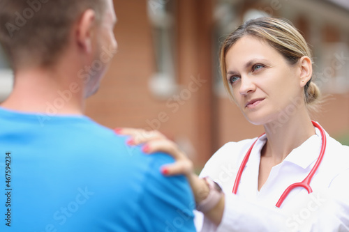 Woman doctor putting hand on patient shoulder to calm down