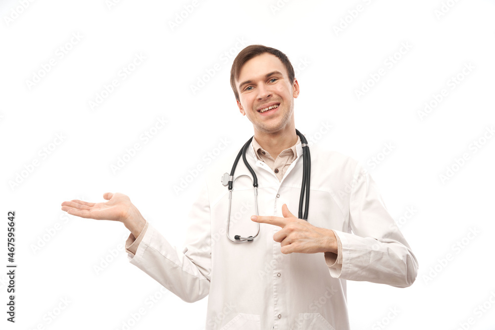Handsome doctor in white medical coat with stethoscope points finger at empty space isolated on white background with copy space. Demonstrates product, excitedly shows something Handsome doctor in white medical coat with stethoscope points finger at empty space isolated on white background with copy space. Demonstrates product, excitedly shows something