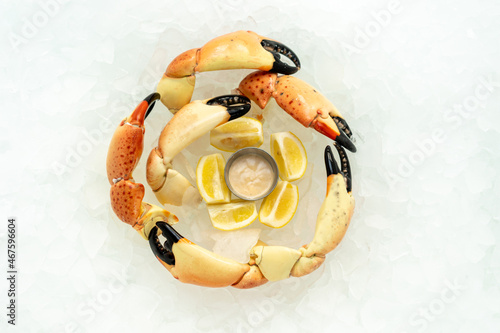 Florida crab claws in a circle, on ice, with dipping sauce, lemons