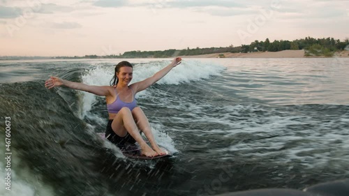 A female surfer jumping on a wakeboard. An experienced wakeboarder splashes water drops into the camera.