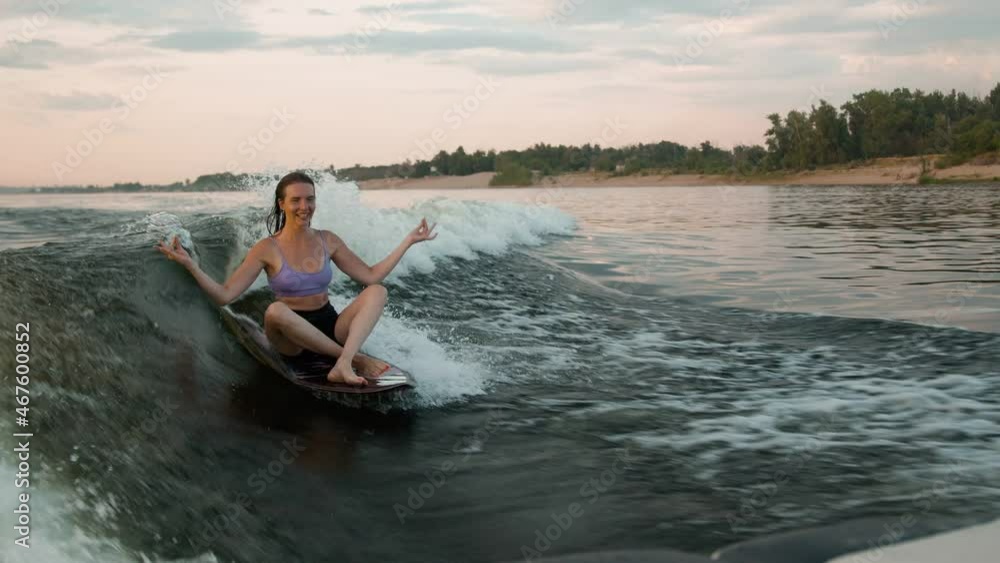 A female surfer jumping on a wakeboard. An experienced wakeboarder splashes water drops into the camera. A female surfer jumping on a wakeboard. An experienced wakeboarder splashes water drops into the camera.