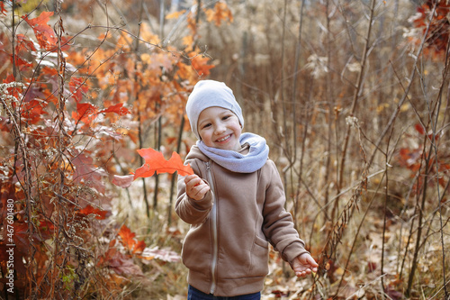 little child playing in the forest with a red leaf