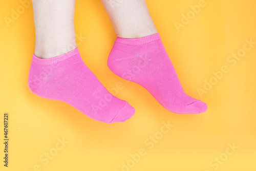 Woman dressed in bright pink socks on a yellow background