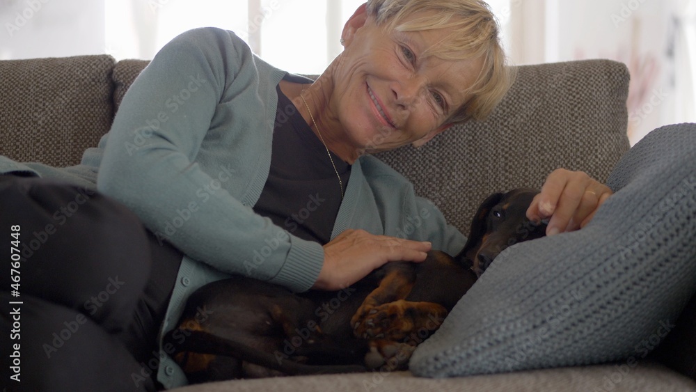 Happy Middle-Aged Woman Petting Her Dog on the Couch Happy Middle-Aged Woman Petting Her Dog on the Couch