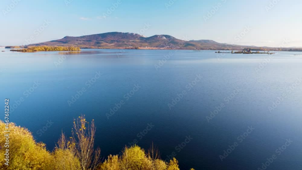 Aerial view on lake with hills on horizon. Moving trees underneath. Aerial view on lake with hills on horizon. Moving trees underneath.