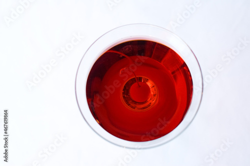 An isolated image of a martini glass with red liquid and a cherry inside on a white background.  Image contains copy space.