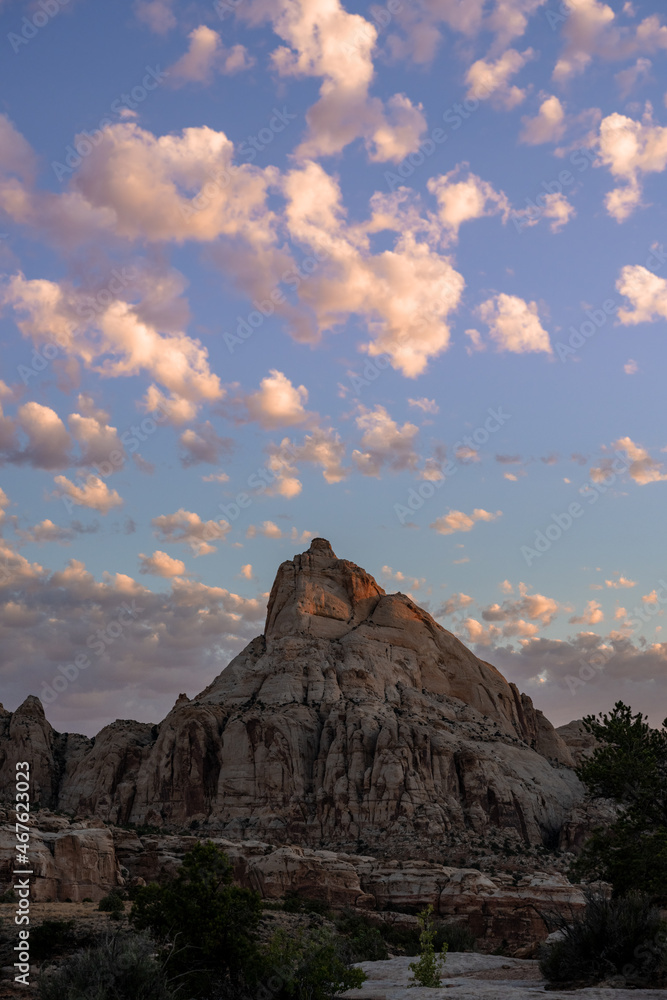 Puffy White Clouds Waft Over Rocks in Desert at Sunrise