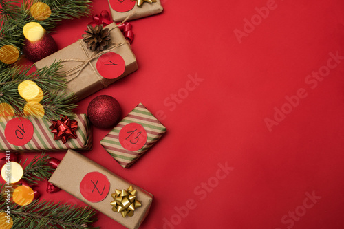 Boxes in kraft paper for the Advent calendar on a red background, Christmas gifts with the dates of the advent calendar top view, place for text.
