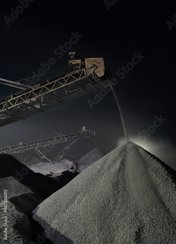 Details of working stone crushing equipment at a mining enterprise at night, long exposure, vertical panorama. Quarry mining machinery.