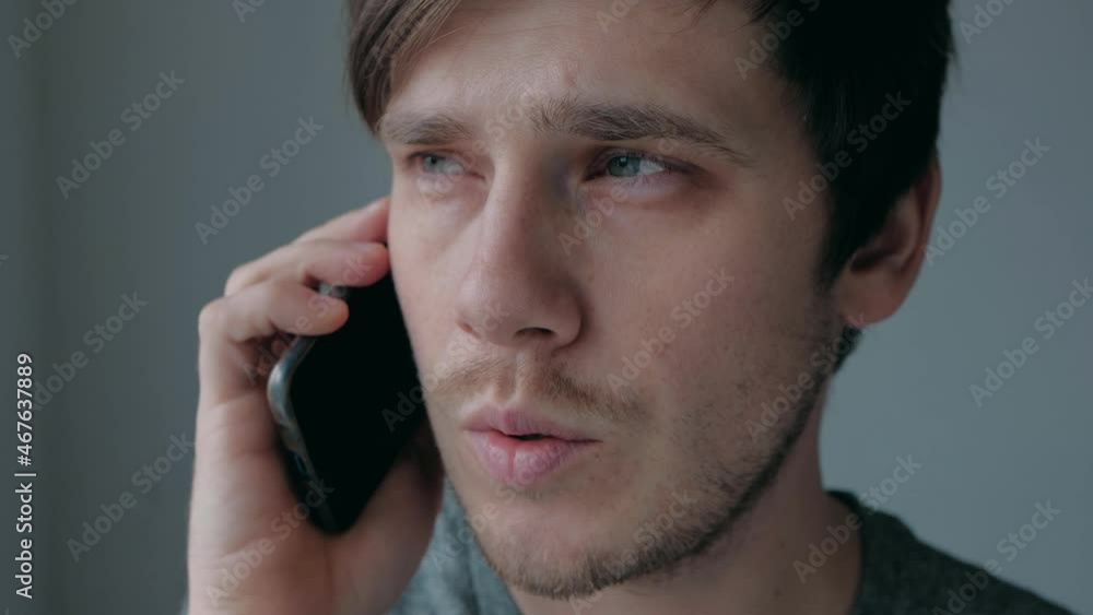 Young guy speak on telephone by window. A good looking man stay by the window and speak on his telephone in the white room. Young guy speak on telephone by window. A good looking man stay by the window and speak on his telephone in the white room.