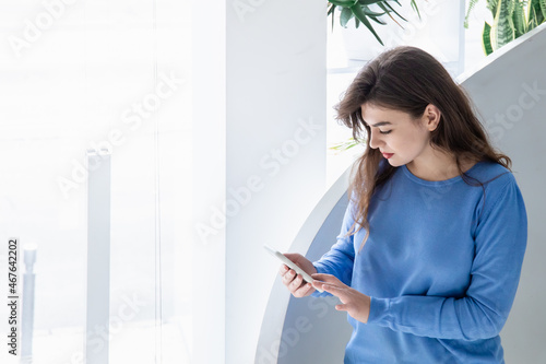 Attractive young woman in a blue sweater uses the phone, copy space.