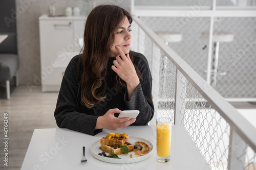 A woman is having breakfast with Belgian waffles and orange juice.