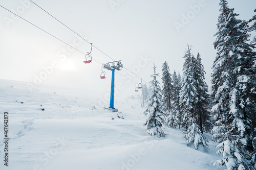 Ski lift with seats going over the mountain and paths from skies and snowboards.