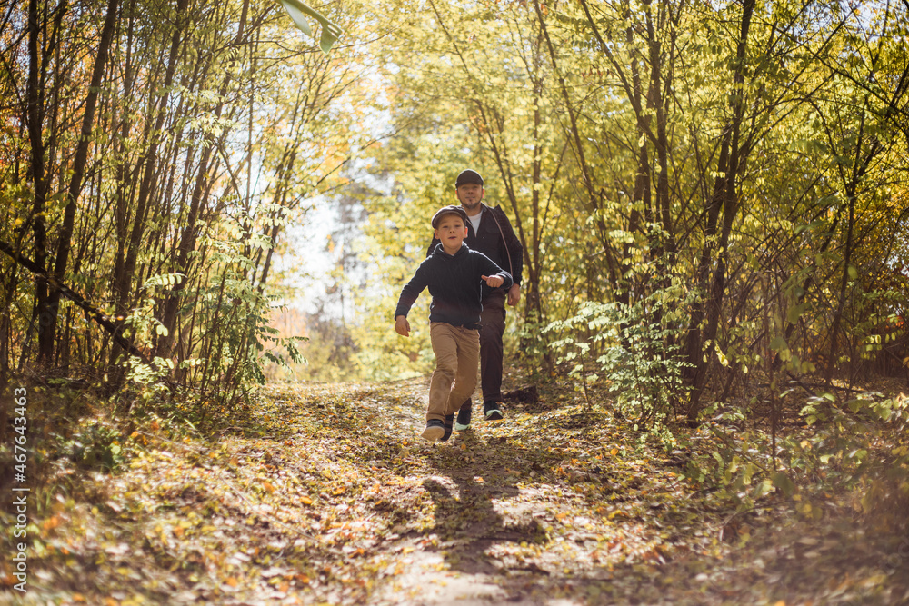 Father and son spend time in forest. Happy dad and child boy enjoying autumn time on vacation in a sunny park. Kids love parents affection and tenderness, lovely family. Father and son spend time in forest. Happy dad and child boy enjoying autumn time on vacation in a sunny park. Kids love parents affection and tenderness, lovely family.
