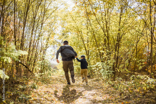 Father and son spend time in forest. Happy dad and child boy enjoying autumn time on vacation in a sunny park. Kids love parents affection and tenderness, lovely family.