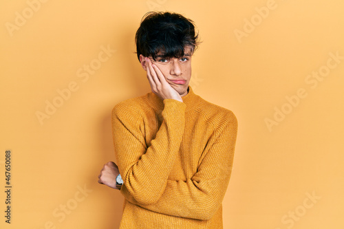 Handsome hipster young man wearing casual yellow sweater thinking looking tired and bored with depression problems with crossed arms.