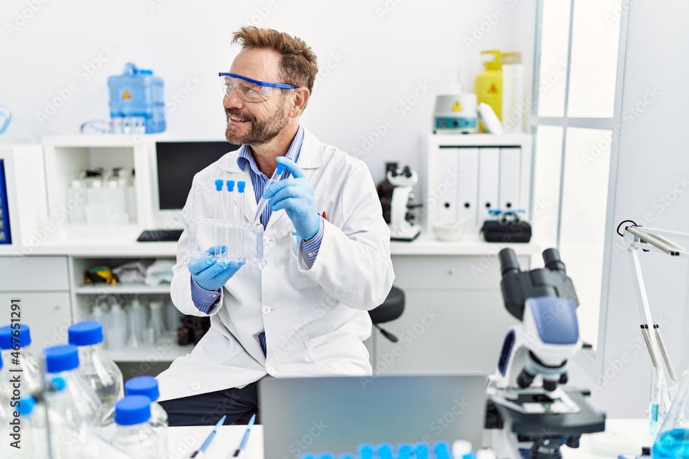 Middle age hispanic man wearing scientist uniform working at laboratory Middle age hispanic man wearing scientist uniform working at laboratory