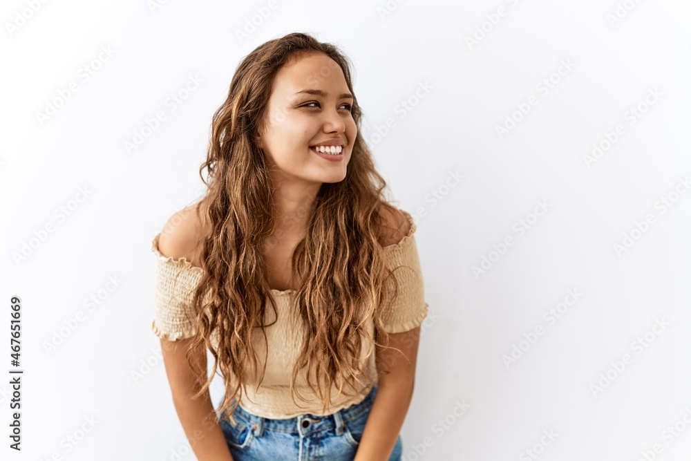 Beautiful hispanic woman standing over isolated while background looking away to side with smile on face, natural expression. laughing confident. Beautiful hispanic woman standing over isolated while background looking away to side with smile on face, natural expression. laughing confident.