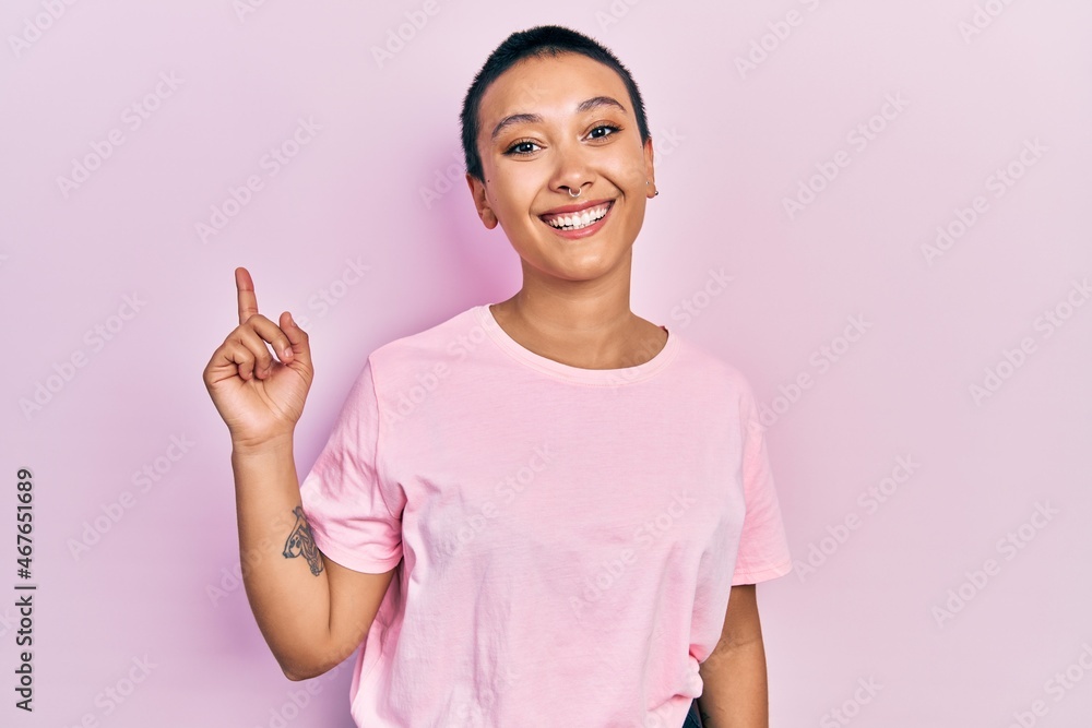 Beautiful hispanic woman with short hair wearing casual pink t shirt with a big smile on face, pointing with hand finger to the side looking at the camera. Beautiful hispanic woman with short hair wearing casual pink t shirt with a big smile on face, pointing with hand finger to the side looking at the camera.