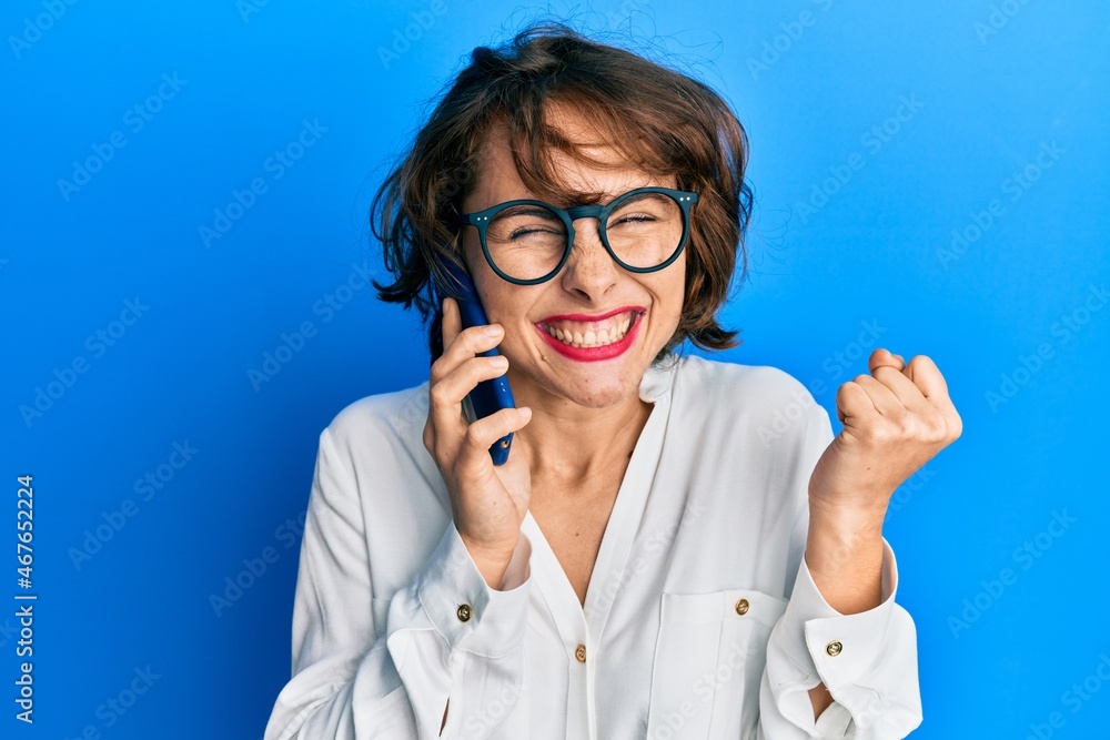 Young brunette woman having conversation talking on the smartphone screaming proud, celebrating victory and success very excited with raised arm Young brunette woman having conversation talking on the smartphone screaming proud, celebrating victory and success very excited with raised arm