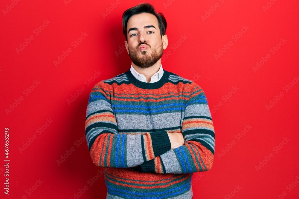 Handsome caucasian man with beard with arms crossed gesture looking at the camera blowing a kiss being lovely and sexy. love expression. Handsome caucasian man with beard with arms crossed gesture looking at the camera blowing a kiss being lovely and sexy. love expression.