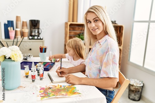 Mother and daughter smiling confident drawing on notebook at art studio