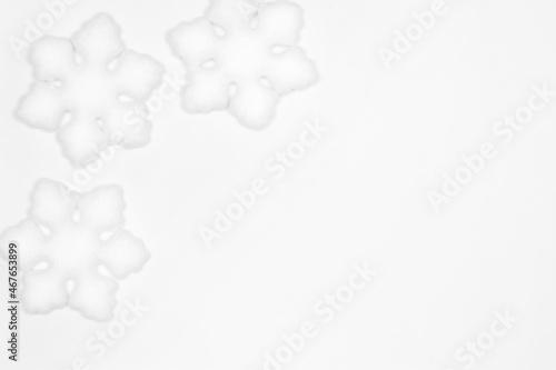 White snowflake decorations frame flat lay on white background. Copy space. Simple winter backdrop