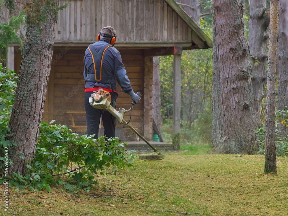The man is cutting the grass. Gasoline lawn mower. The man is cutting the grass. Gasoline lawn mower.