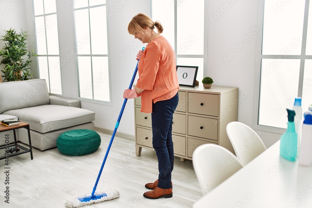 Middle age woman smiling happy washing floor at home. Middle age woman smiling happy washing floor at home.