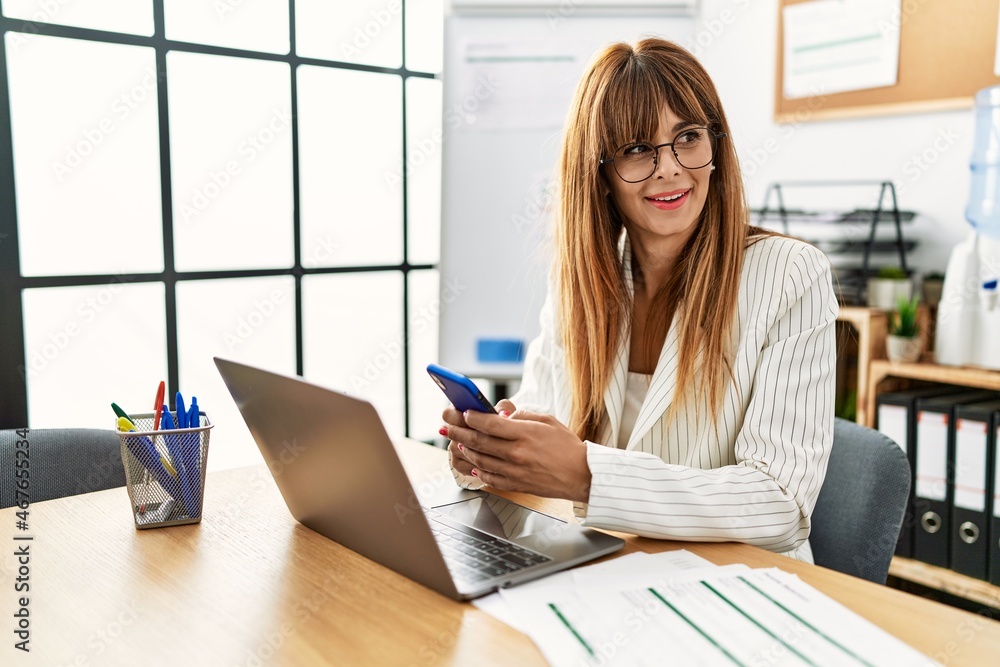 Young hispanic businesswoman working using smartphone and laptop at the office. Young hispanic businesswoman working using smartphone and laptop at the office.