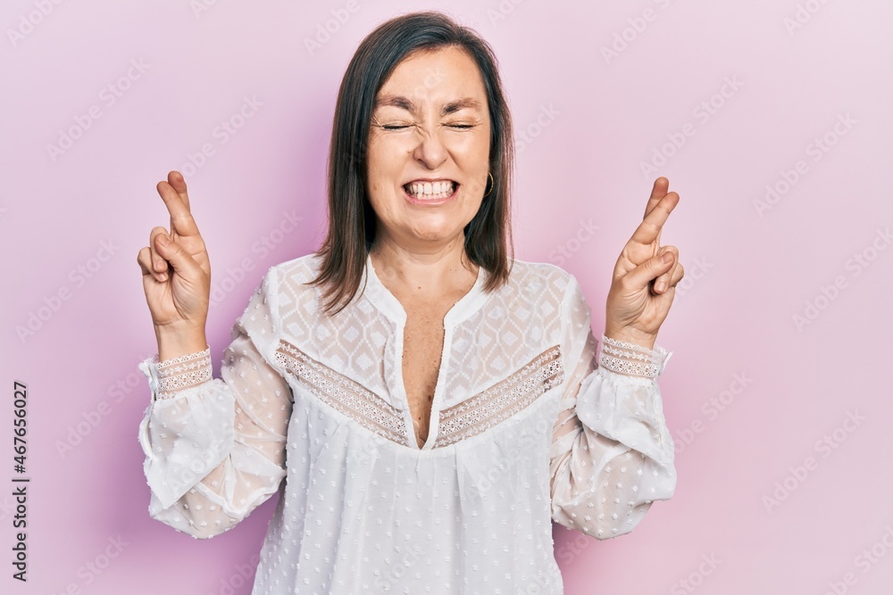 Middle age hispanic woman wearing casual clothes gesturing finger crossed smiling with hope and eyes closed. luck and superstitious concept. Middle age hispanic woman wearing casual clothes gesturing finger crossed smiling with hope and eyes closed. luck and superstitious concept.