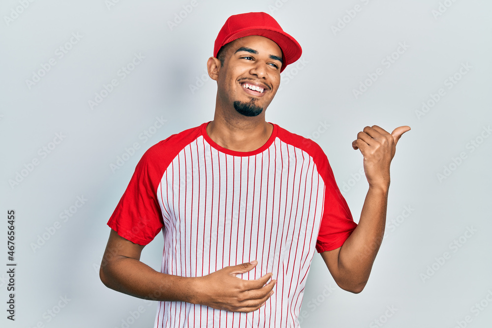 Young african american man wearing baseball uniform smiling happy and positive, thumb up doing excellent and approval sign Young african american man wearing baseball uniform smiling happy and positive, thumb up doing excellent and approval sign