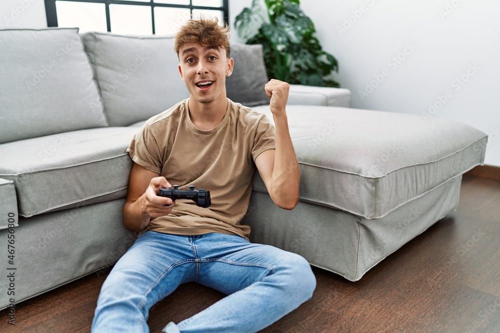 Young caucasian man playing video game holding controller at home screaming proud, celebrating victory and success very excited with raised arms Young caucasian man playing video game holding controller at home screaming proud, celebrating victory and success very excited with raised arms