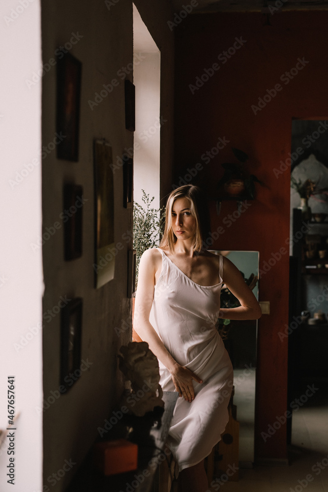 talented sculptor girl in light negligee stands in pottery workshop near large window. concept is beauty and art. talented sculptor girl in light negligee stands in pottery workshop near large window. concept is beauty and art.