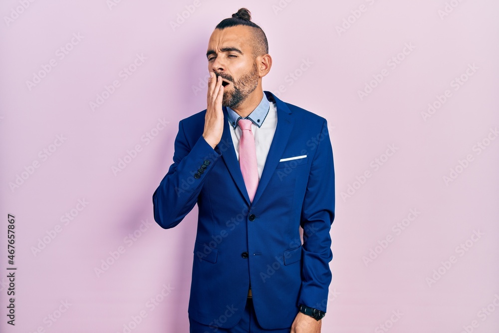 Young hispanic man wearing business suit and tie bored yawning tired covering mouth with hand. restless and sleepiness. Young hispanic man wearing business suit and tie bored yawning tired covering mouth with hand. restless and sleepiness.