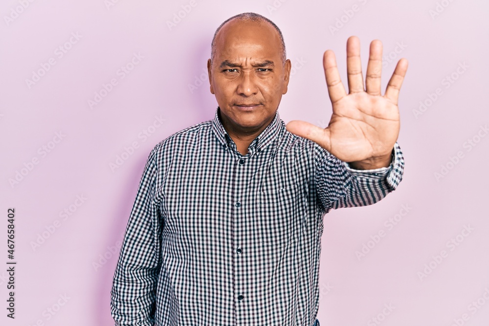 Middle age latin man wearing casual clothes doing stop sing with palm of the hand. warning expression with negative and serious gesture on the face. Middle age latin man wearing casual clothes doing stop sing with palm of the hand. warning expression with negative and serious gesture on the face.