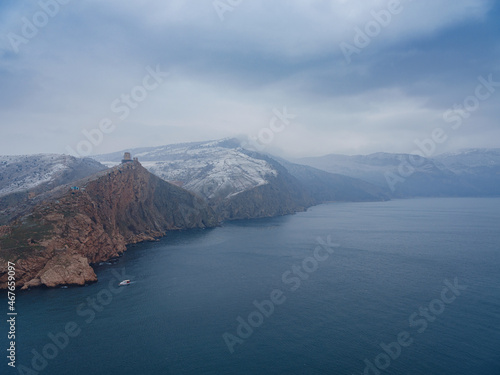 ancient castle ruins on a beautiful rock rise above the sea. winter season, snow is falling.