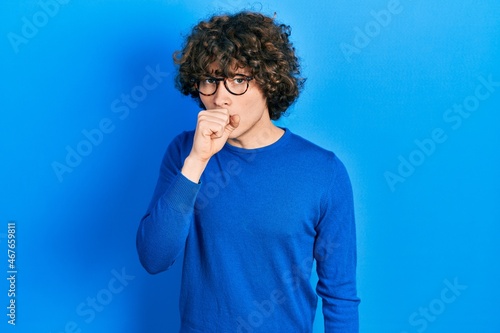 Handsome young man wearing casual clothes and glasses feeling unwell and coughing as symptom for cold or bronchitis. health care concept.