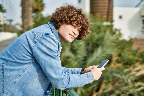 Young hispanic man using smartphone at the park