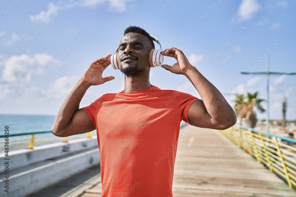Young african american man smiling confident listening to music at seaside