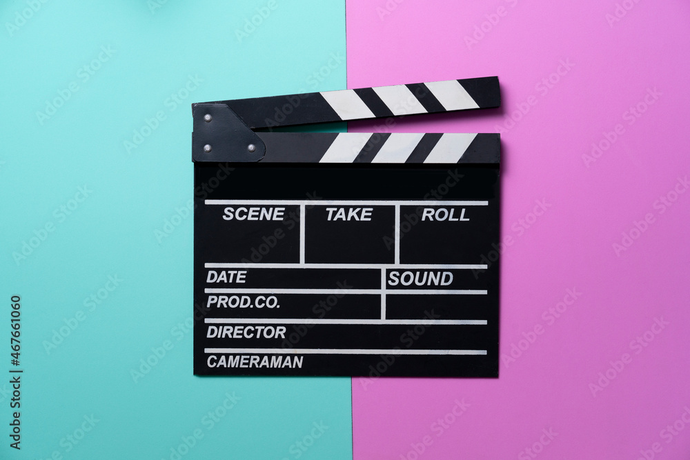 movie clapper on green and pink table background ; film, cinema and video photography concept
