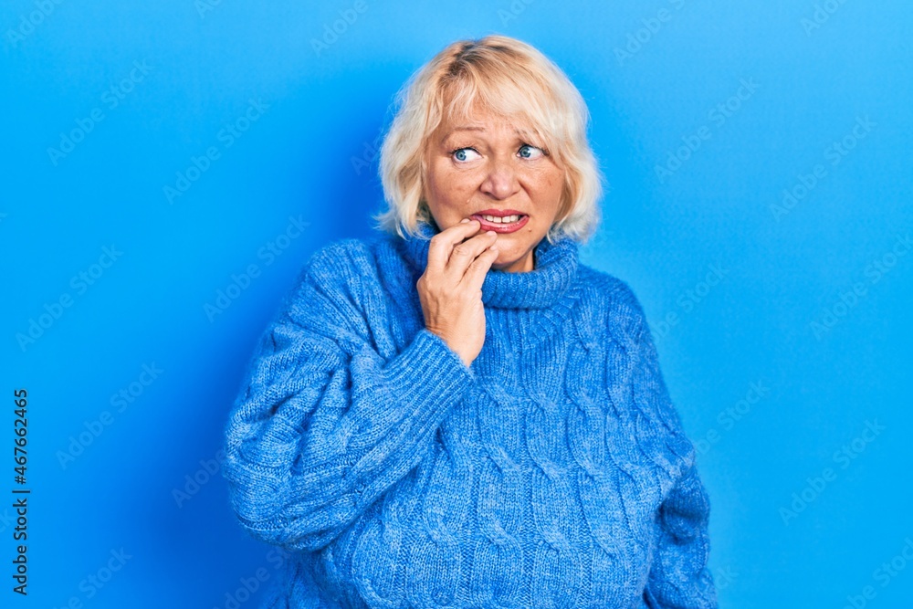 Middle age blonde woman wearing casual clothes looking stressed and nervous with hands on mouth biting nails. anxiety problem. Middle age blonde woman wearing casual clothes looking stressed and nervous with hands on mouth biting nails. anxiety problem.