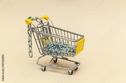Metal shopping cart on a beige background.