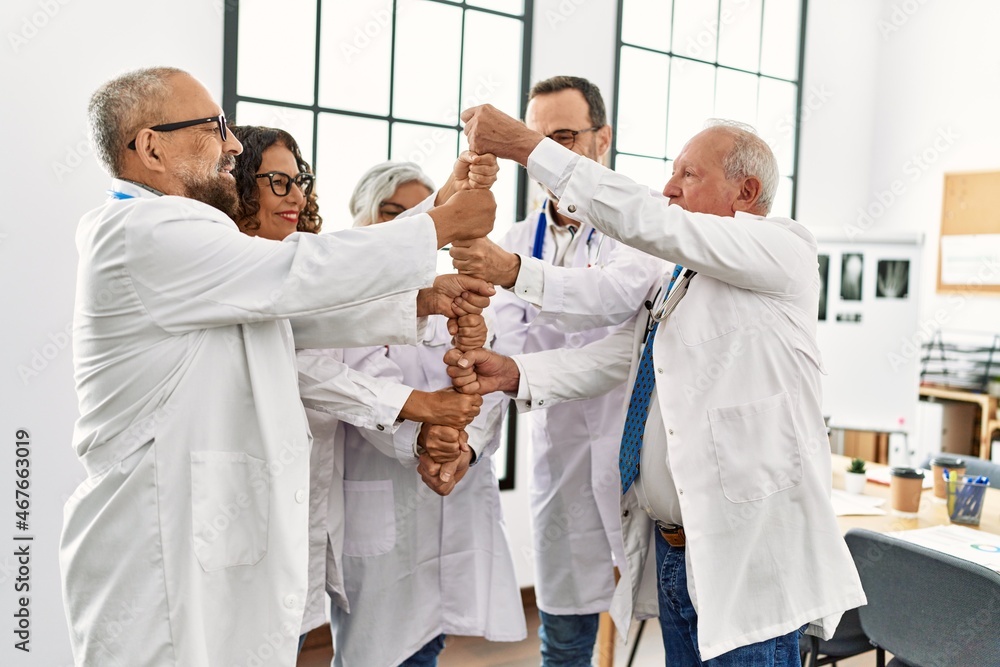 Obraz premium Group of middle age doctor smiling happy bulding tower with fists in a medical meeting at the clinic office.