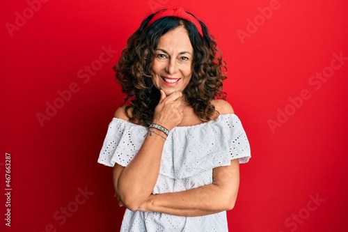 Fotografie Middle age hispanic woman wearing casual clothes looking confident at the camera smiling with crossed arms and hand raised on chin