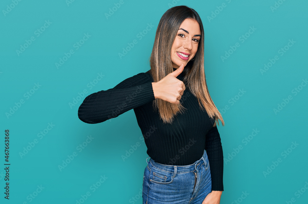 Young hispanic woman wearing casual clothes doing happy thumbs up gesture with hand. approving expression looking at the camera showing success. Young hispanic woman wearing casual clothes doing happy thumbs up gesture with hand. approving expression looking at the camera showing success.
