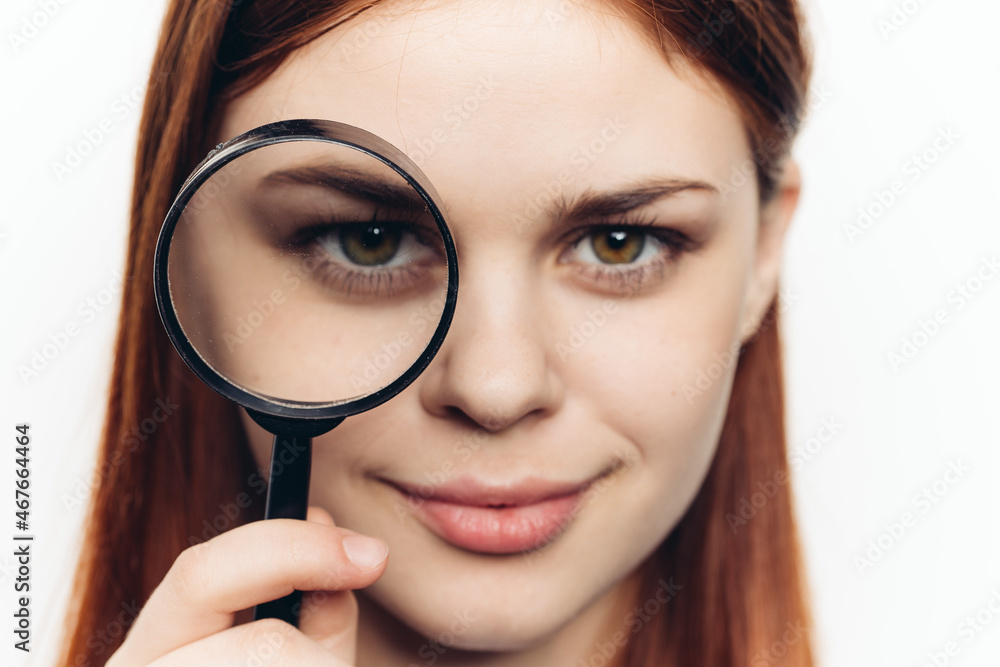 pretty woman grimacing with magnifying glass near face close-up pretty woman grimacing with magnifying glass near face close-up