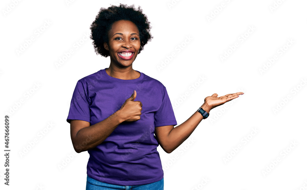 African american woman with afro hair wearing casual purple t shirt showing palm hand and doing ok gesture with thumbs up, smiling happy and cheerful African american woman with afro hair wearing casual purple t shirt showing palm hand and doing ok gesture with thumbs up, smiling happy and cheerful