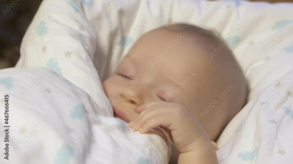Baby wrapped in a blanket falls asleep, six month old infant face closeup. High quality 4k footage Baby wrapped in a blanket falls asleep, six month old infant face closeup. High quality 4k footage