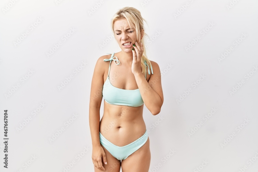 Fototapeta premium Young caucasian woman wearing bikini over isolated background touching mouth with hand with painful expression because of toothache or dental illness on teeth. dentist